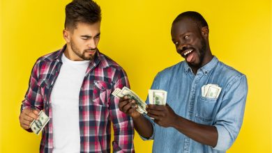 playful african man joking with beautiful european man while the holding money