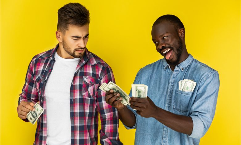 playful african man joking with beautiful european man while the holding money