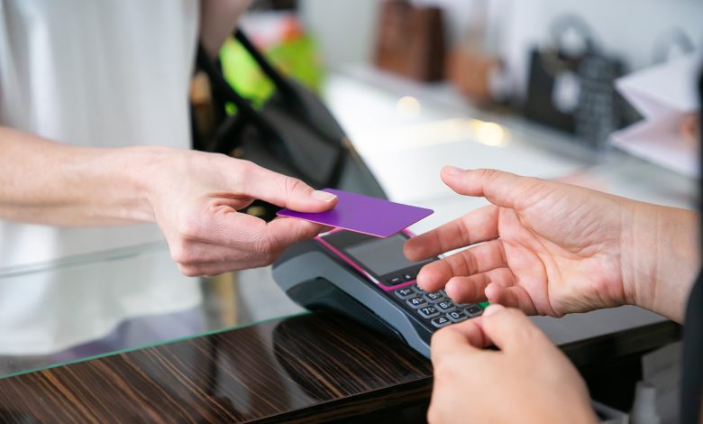 customer giving credit card to cashier over desk with pos terminal for payment cropped shot closeup of hands shopping concept