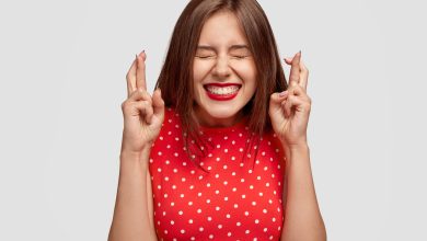 pleased attractive european woman makes wish to win raises hands with crossed fingers waits for lottery results closes eyes